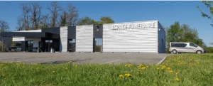 Façade d'une chambre funéraire moderne avec parking et espace vert.