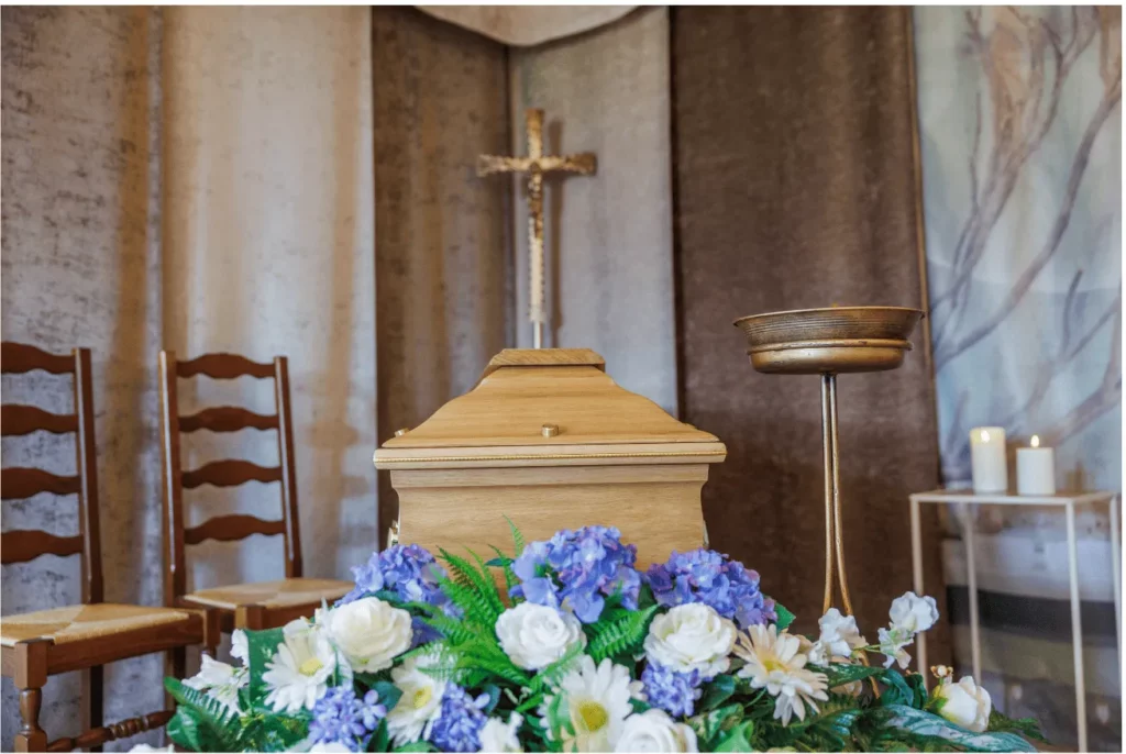 Cercueil en bois orné de fleurs fraîches dans un salon funéraire.