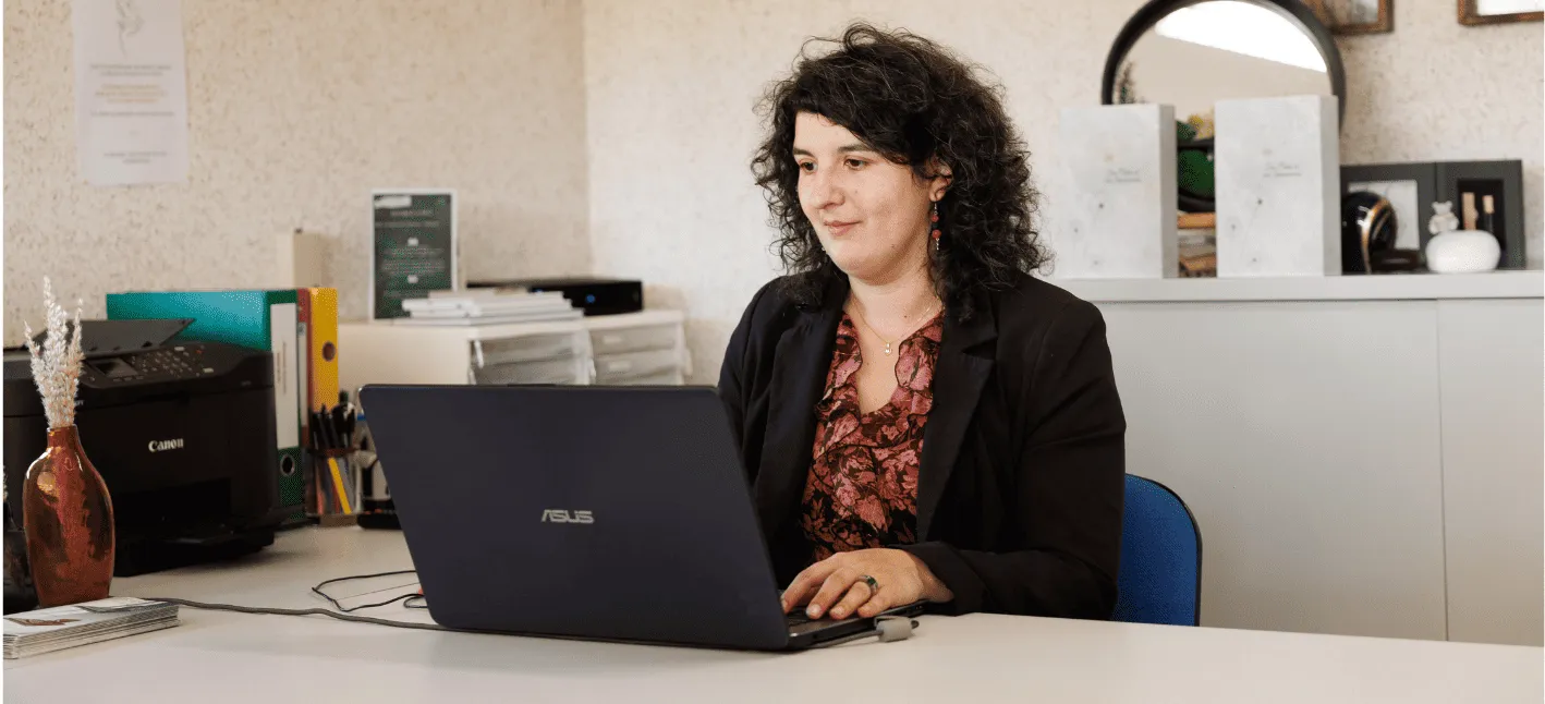 Conseillère funéraire travaillant sur un ordinateur portable dans son bureau.